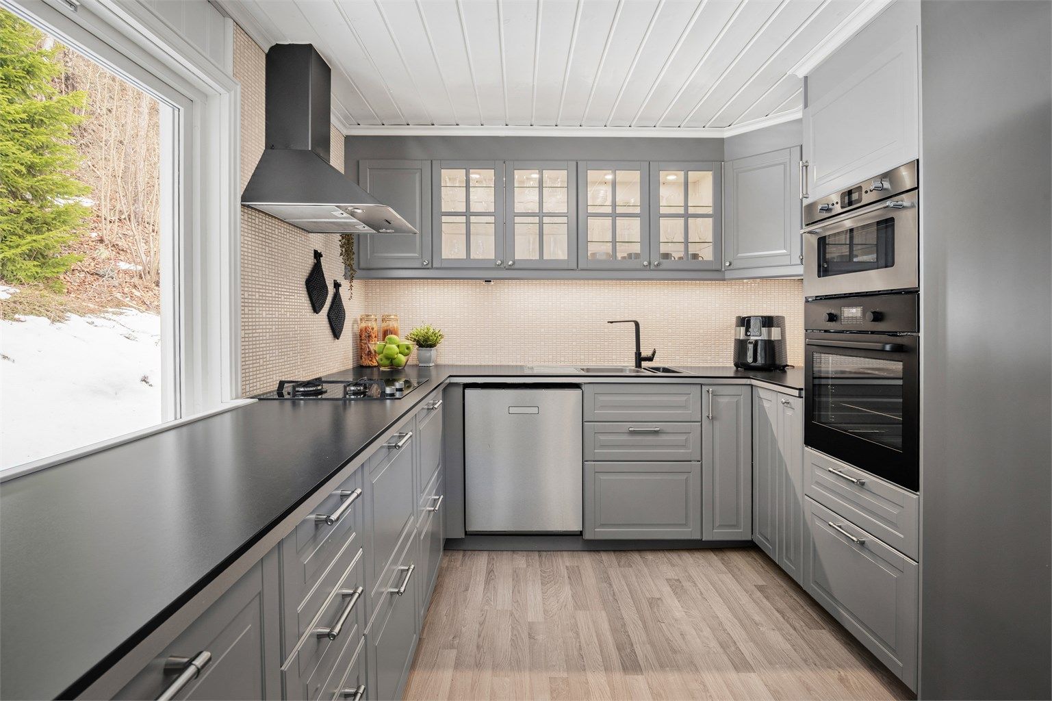 Pent IKEA kjøkken med innredning med profilerte fronter. Benkeplaten er av laminat. Integrert gassbluss, induksjonstopp, micro og stekeovn. Plass til oppvaskmaskin kjøle/fryseskap.