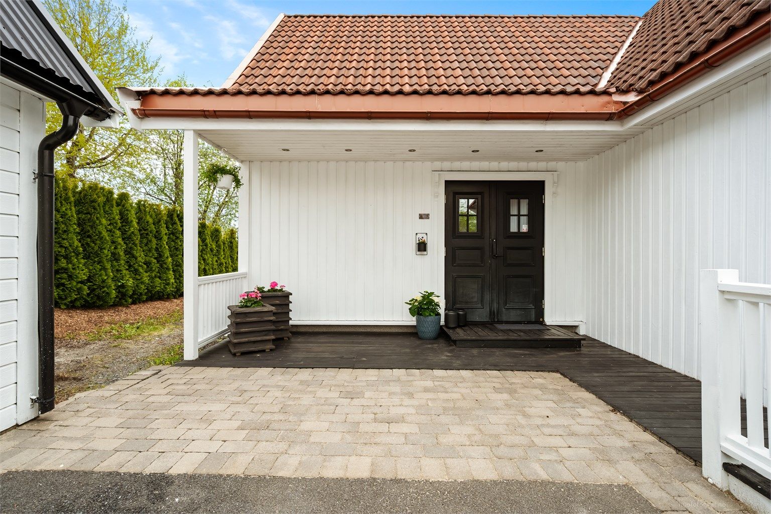 Overbygd inngangsparti med en platting på 10 kvm med utvendige downlights i tak.