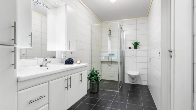 Romslig, flislagt baderom på ca 7m², baderommet er kombinert med vaskerom som er adskilt med skyvedør