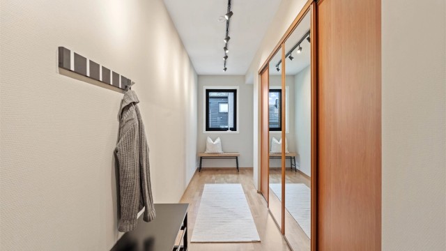 Romslig entré med stor skyvedørsgarderobe som gir rikelig med oppbevaringsplass.