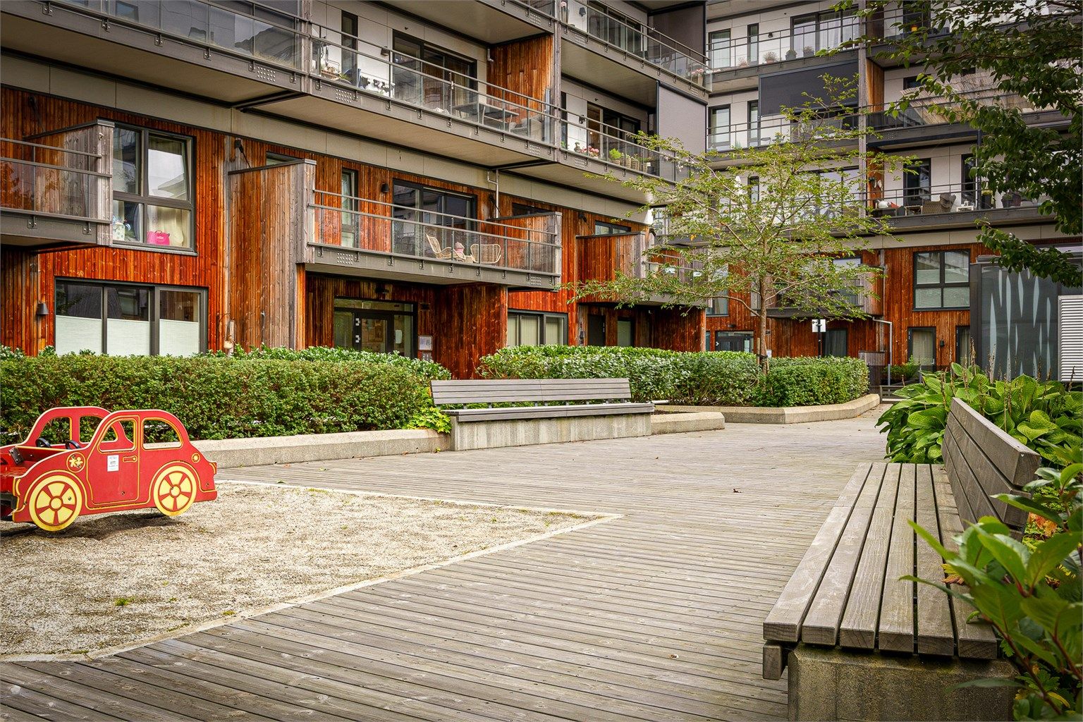 Felles, bilfritt gårdsrom med sittebenker og lekeområde for beboerne.