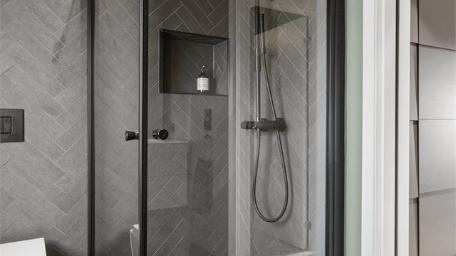 Dusjnisje med innfellbare dører og regnskogdusj, integrert hylle i dusjvegg.