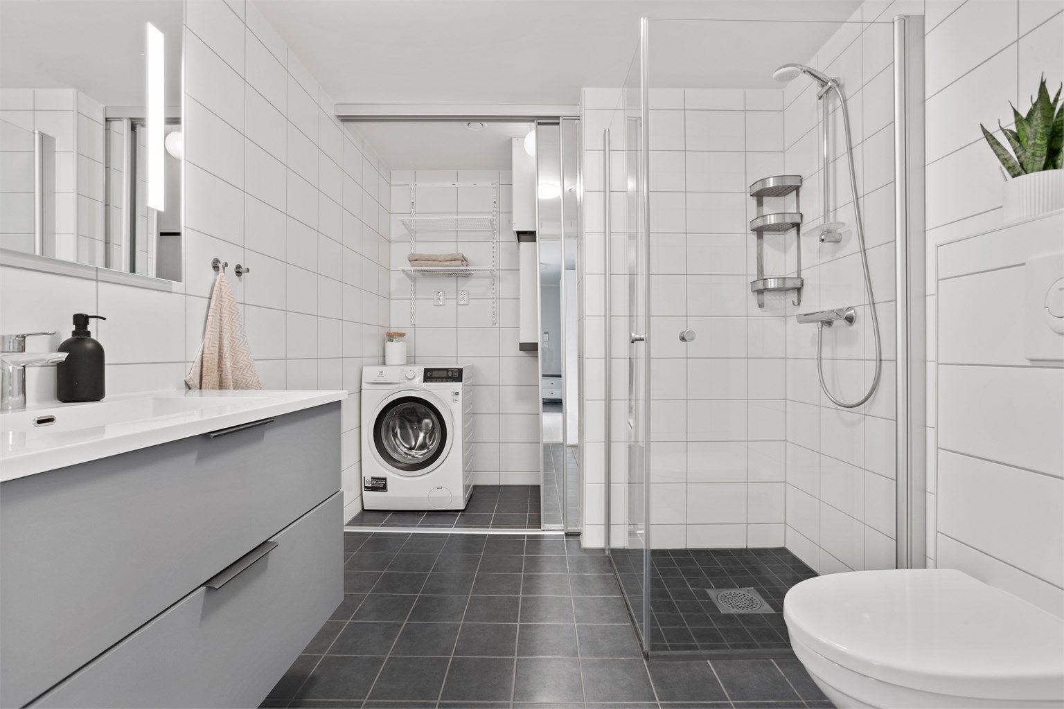 Badet har praktisk skyvedør for å skjule opplegg for vaskemaskin og balansert ventilasjonsaggregat. 