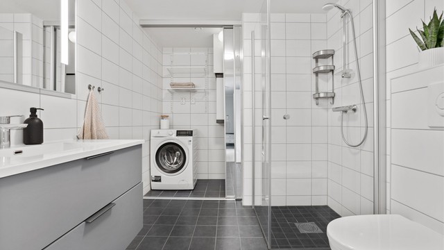 Badet har praktisk skyvedør for å skjule opplegg for vaskemaskin og balansert ventilasjonsaggregat.