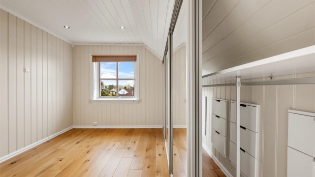 Soverommet har panel i taket og parkett på gulvet, noe som gir en lys og trivelig atmosfære.