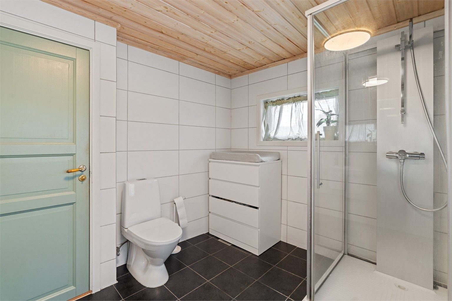 Badet er utstyrt med dusjkabinett og toalett.