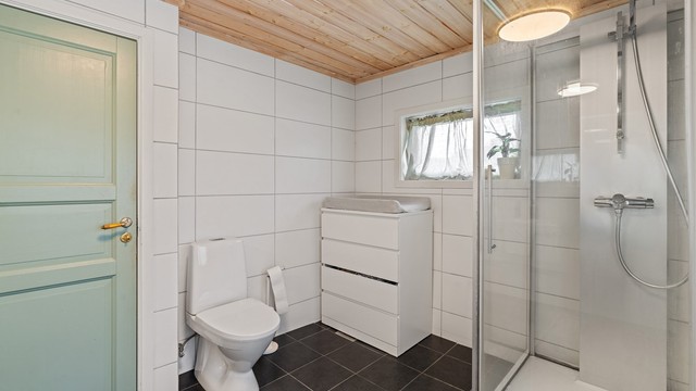 Badet er utstyrt med dusjkabinett og toalett.