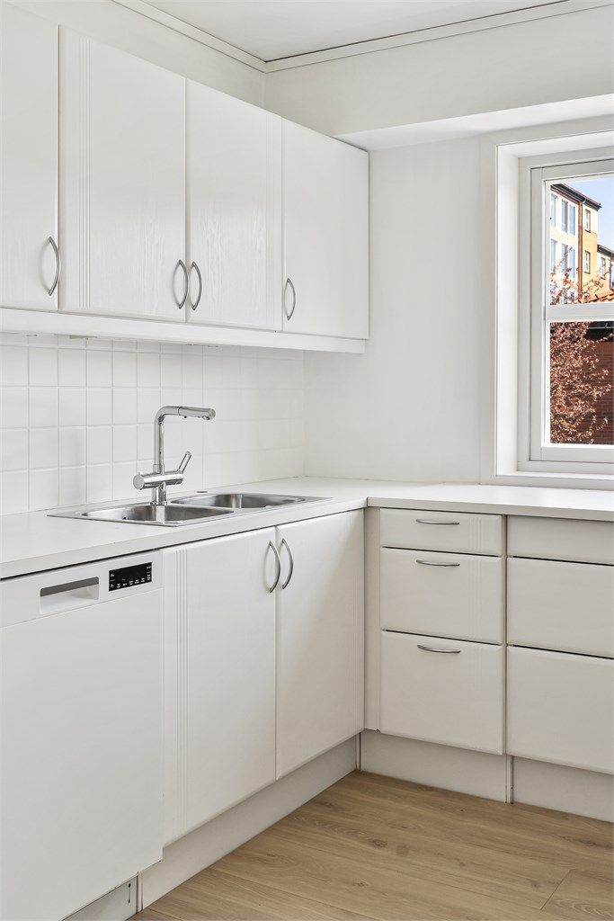 Kjøkkeninnredningen har laminert benkeplate, nedfelt vask og fliser over benken.