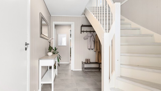 Fra gangen fører trappen opp til andre etasje. Varmepumpen er strategisk plassert i trappegangen for effektiv varmefordeling.