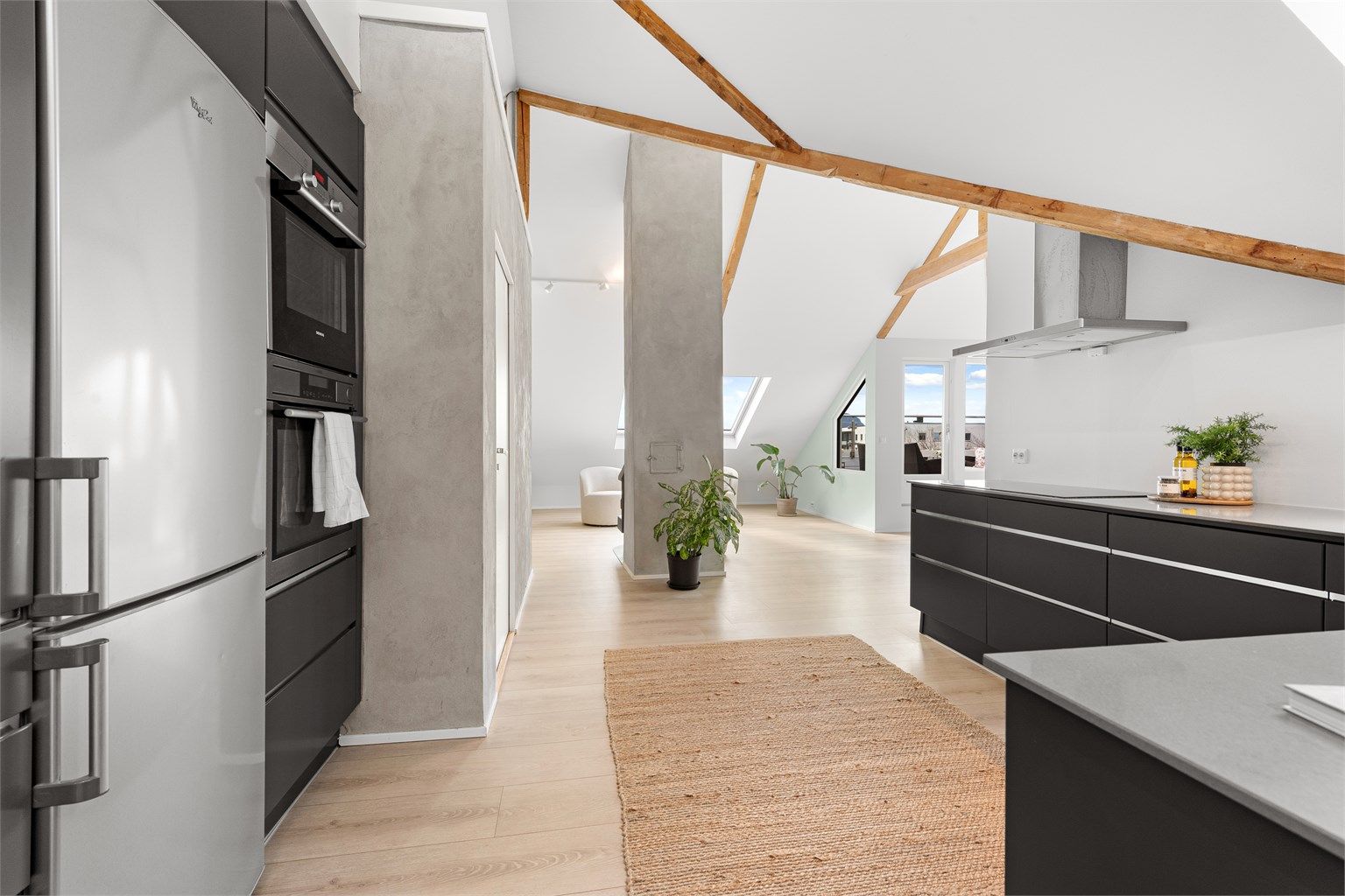 Leilighetens åpne og luftige karakter forsterkes av de synlige takbjelkene og den gode takhøyden.