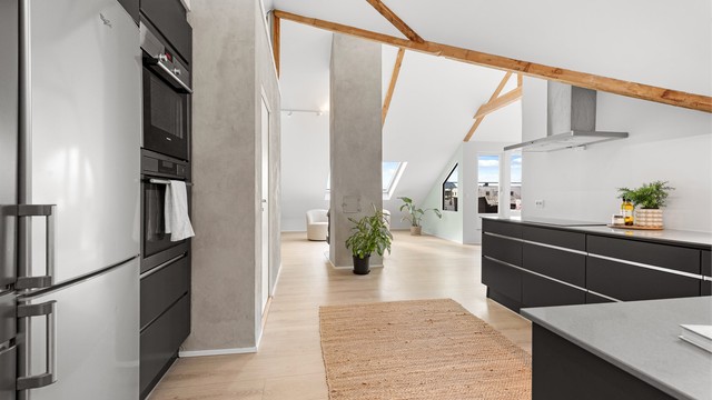 Leilighetens åpne og luftige karakter forsterkes av de synlige takbjelkene og den gode takhøyden.