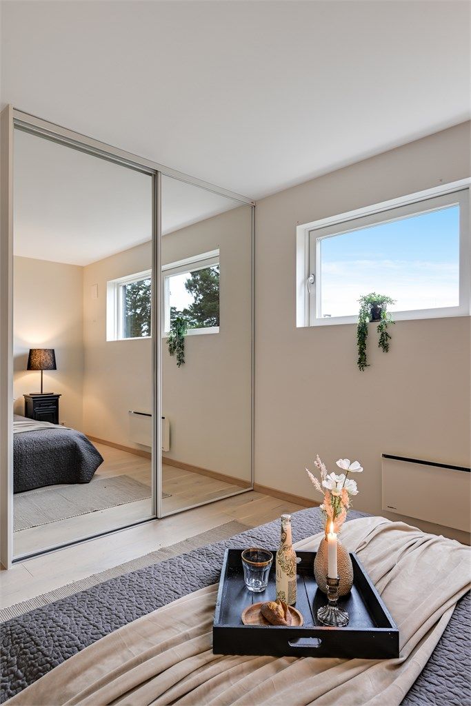 En skyvedørsgarderobe med speilfronter gir rikelig med oppbevaringsplass og bidrar til romfølelsen.