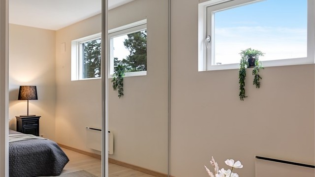 En skyvedørsgarderobe med speilfronter gir rikelig med oppbevaringsplass og bidrar til romfølelsen.