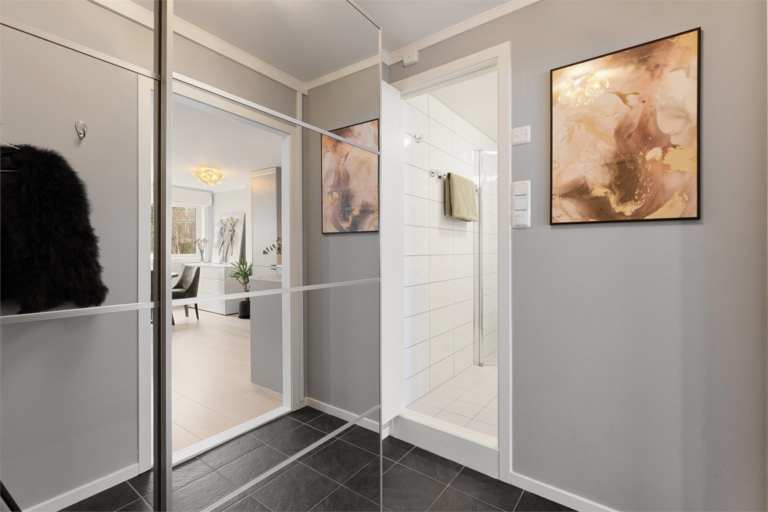 Fra entréen er det direkte tilgang til badet, og videre inn til leilighetens åpne oppholdsrom.