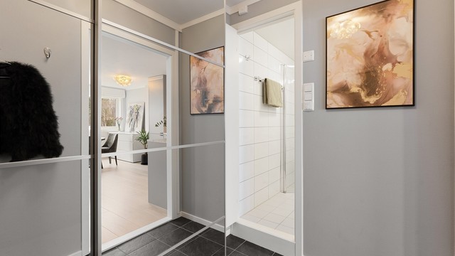 Fra entréen er det direkte tilgang til badet, og videre inn til leilighetens åpne oppholdsrom.