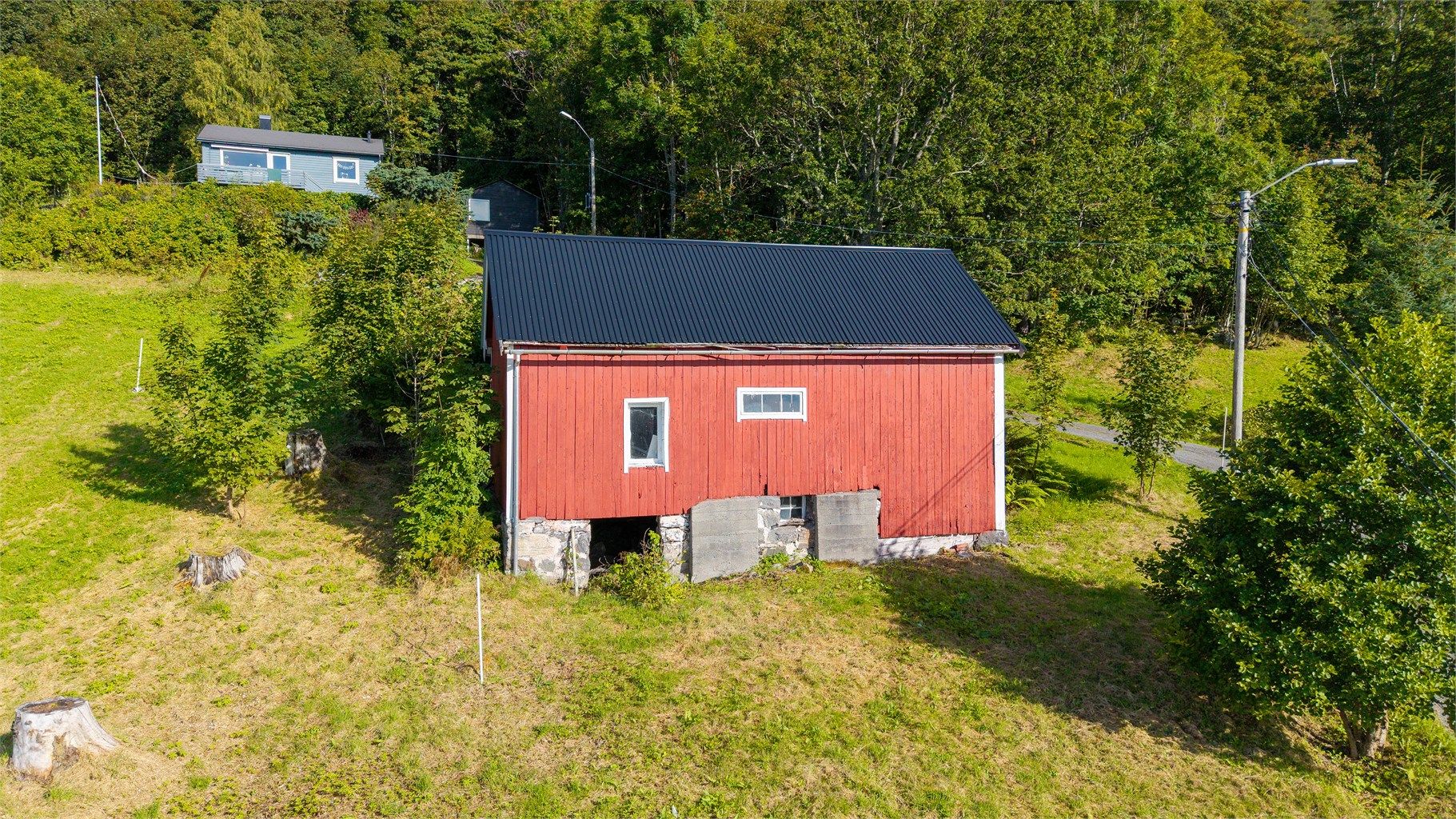 Den frittstående løen er oppført i trekonstruksjoner med stående kledning og metalltak.