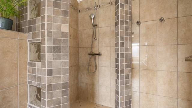 I tillegg til badekar har badet en separat dusjnisje med flislagte vegger.