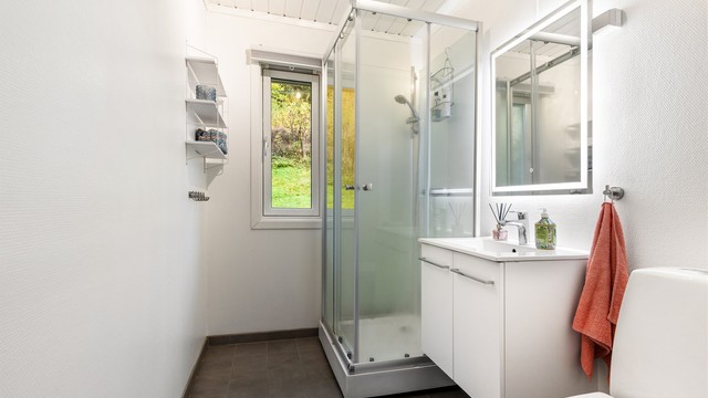 Baderom fra byggeår med enkelte oppgraderinger utført i 2010 ifølge huseier. Vegghengt servantinnredning med ovenpåligende servant med armatur. Baderommet har dusjkabinett med dusjarmatur og gulvstående toalett.