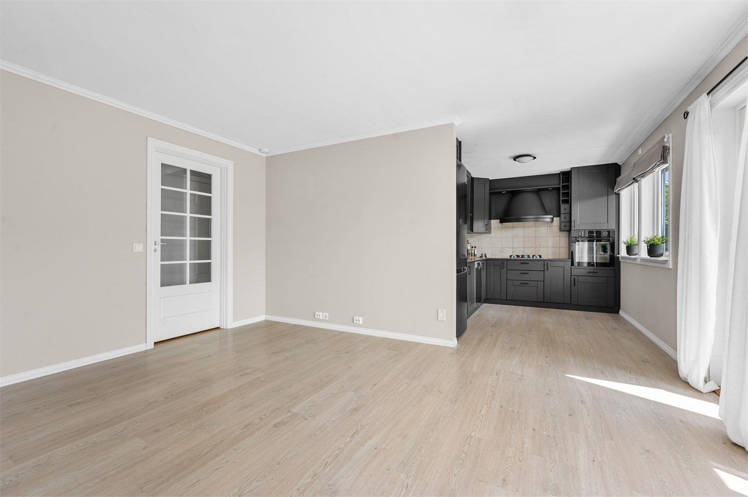 Åpen stue/kjøkken med innredning i mørke fronter- en fin kontrast til den lyse parketten og fargene i stue/kjøkken.