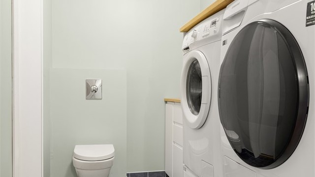 Praktisk vaskerom med flislagt gulv med gulvvarme, opplegg for vaskemaskin og tørketrommel.