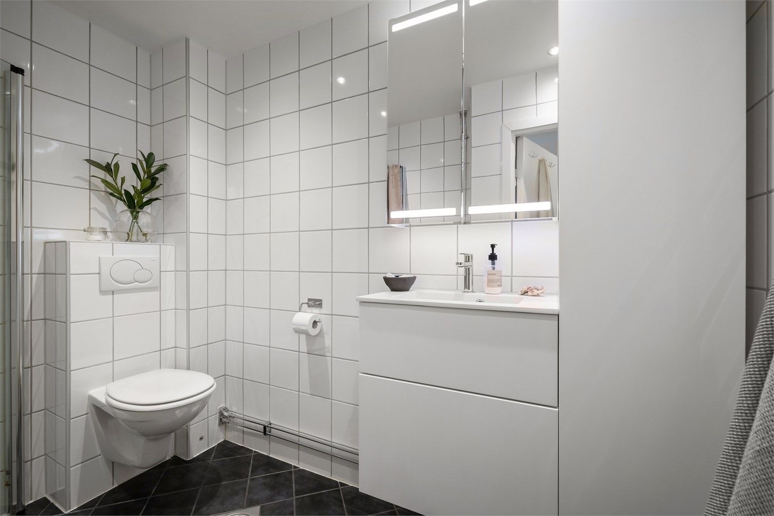 Et pent, flislagt bad med varmekabler, downlights i himling og opplegg for vaskemaskin