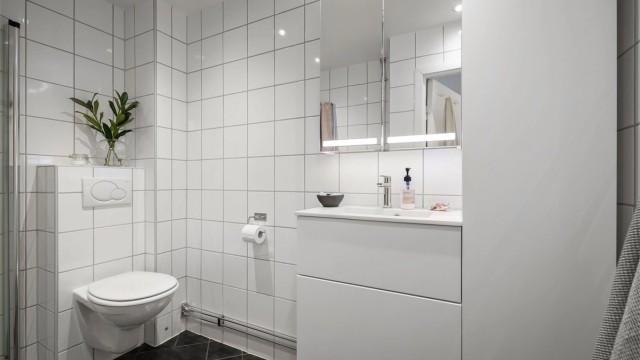 Et pent, flislagt bad med varmekabler, downlights i himling og opplegg for vaskemaskin