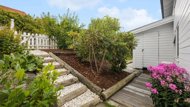Eiendommen er pent og gjennomført opparbeidet med frodige bed, vakker beplantning og et sjarmerende hvitt stakittgjerde. På baksiden av boligen finnes praktiske utendørsboder.