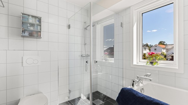Badet er utstyrt med både badekar og et dusjhjørne med innfellbare glassdører