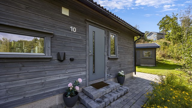 Et velholdt inngangsparti med belegningsstein og elbillader.