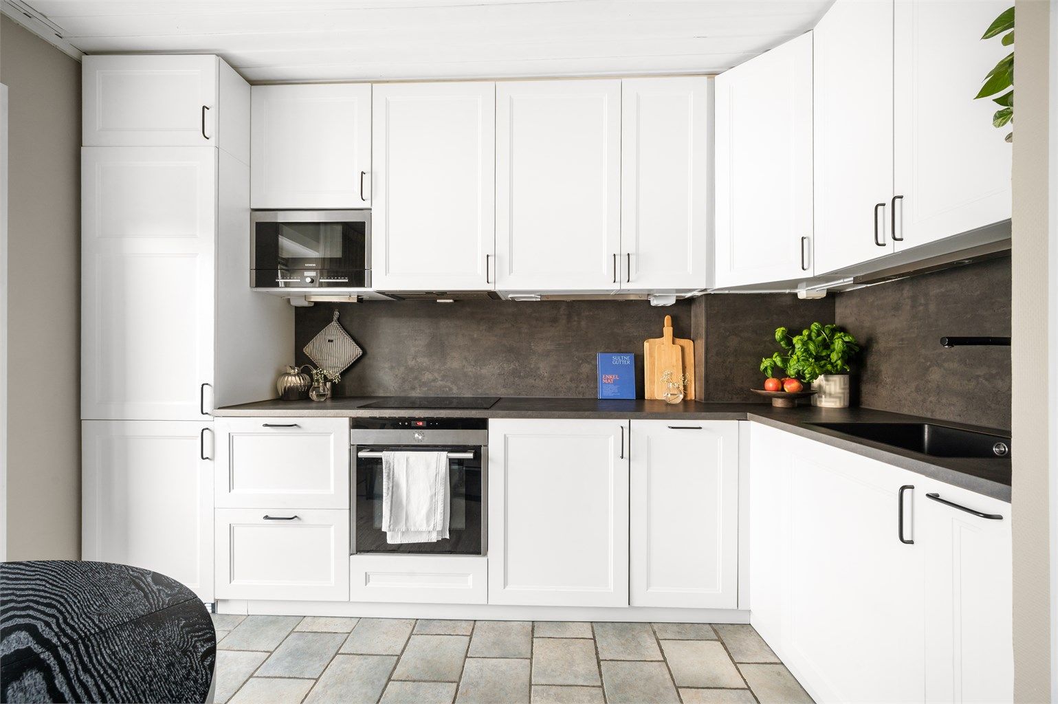 Innredningen inkluderer induksjonstopp, stekeovn, mikro, oppvaskmaskin og et kombinert kjøl-/fryseskap.