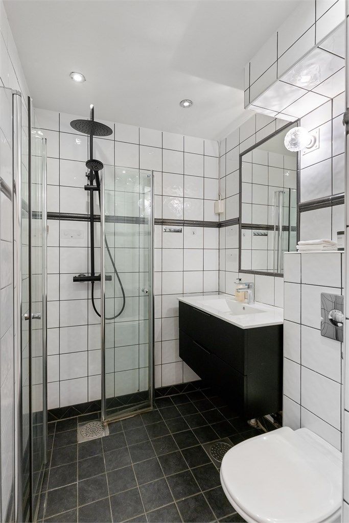 Rommet er utstyrt med vegghengt toalett, servantinnredning og dusjhjørne med regnfallsdusj.