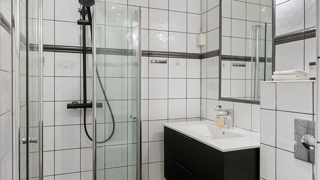 Rommet er utstyrt med vegghengt toalett, servantinnredning og dusjhjørne med regnfallsdusj.