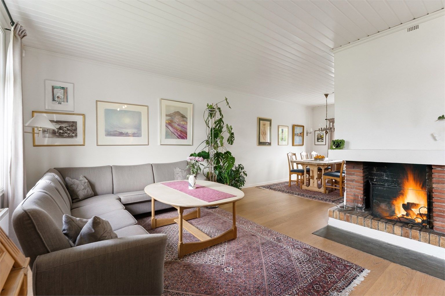 Stuen har en åpen teglsteinspeis som gir en lun og god atmosfære.