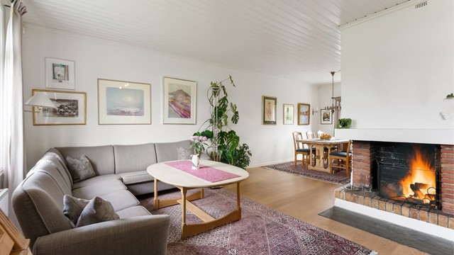 Stuen har en åpen teglsteinspeis som gir en lun og god atmosfære.