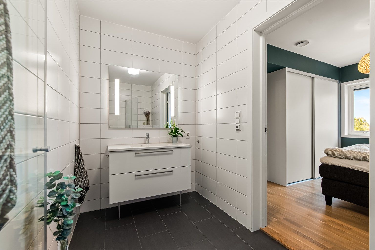 Badet er innredet med servant med skuffeinnredning, speil med belysning og vegghengt toalett.