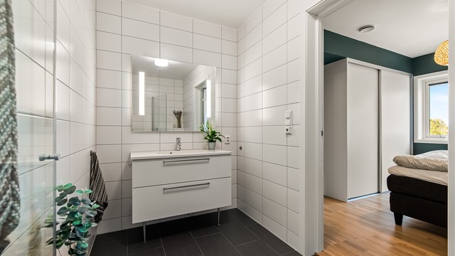 Badet er innredet med servant med skuffeinnredning, speil med belysning og vegghengt toalett.