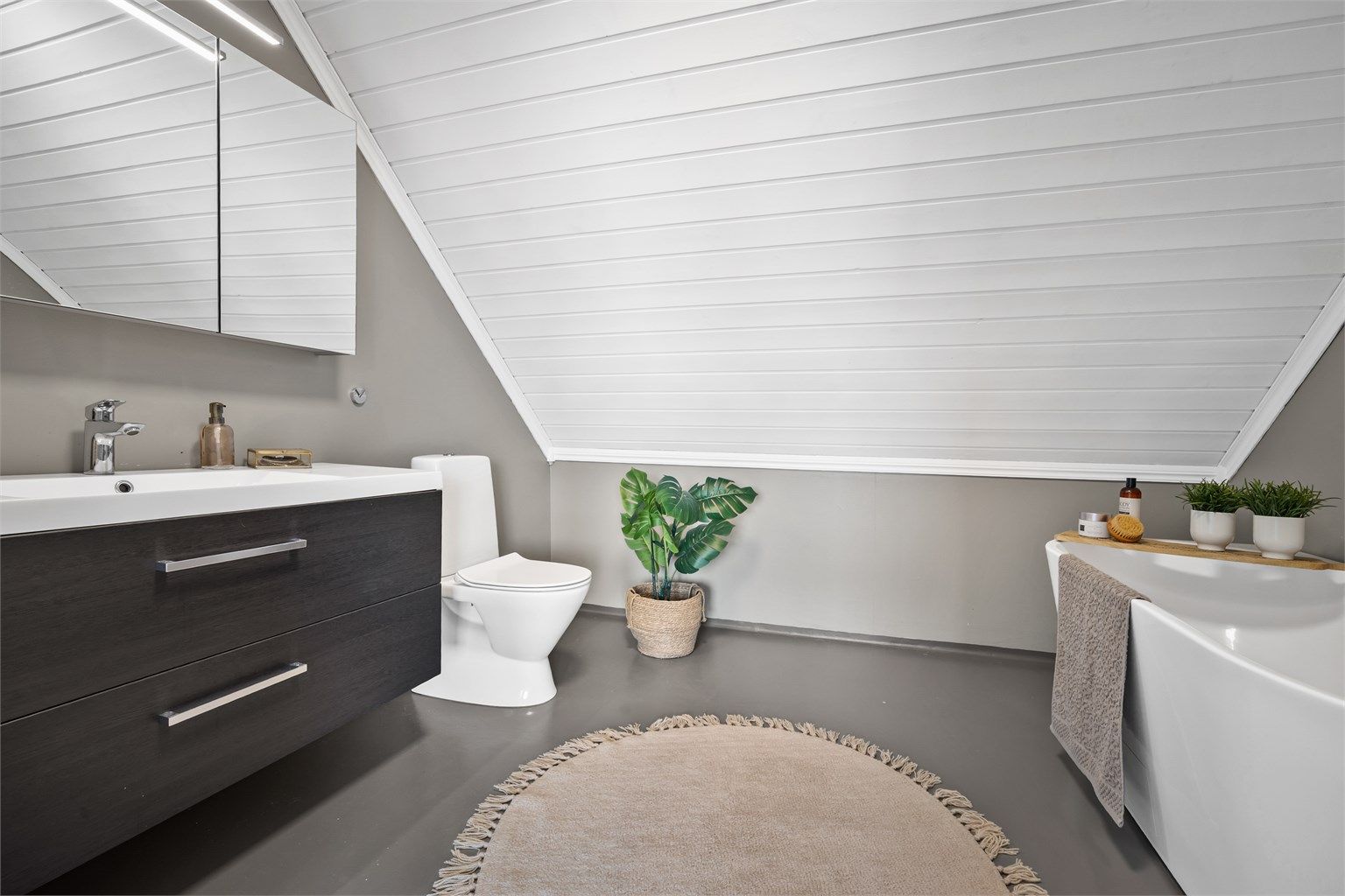 Rommet er utstyrt med badekar, toalett og en servant med god oppbevaringsplass.