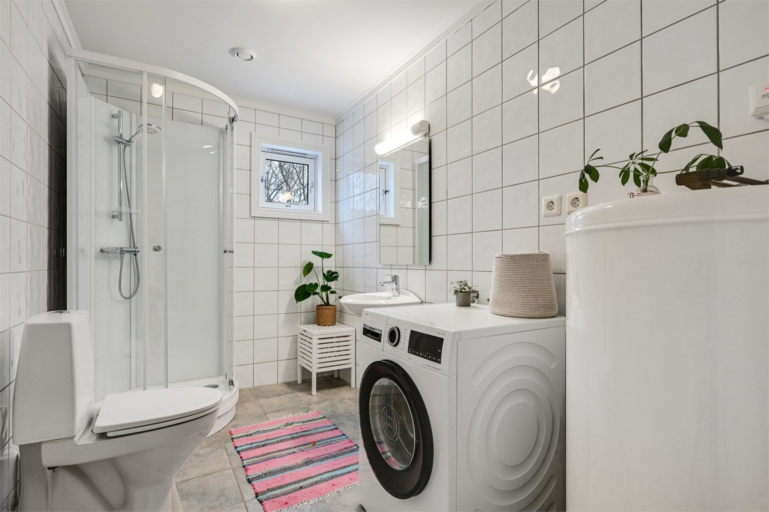 Flislagt bad i første etasje med toalett, dusj og servant.