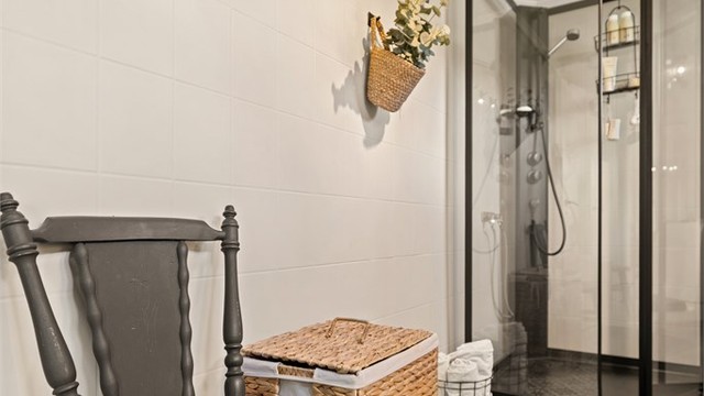 Badet har mønstrede gulvfliser og dusjkabinett med sorte profiler.