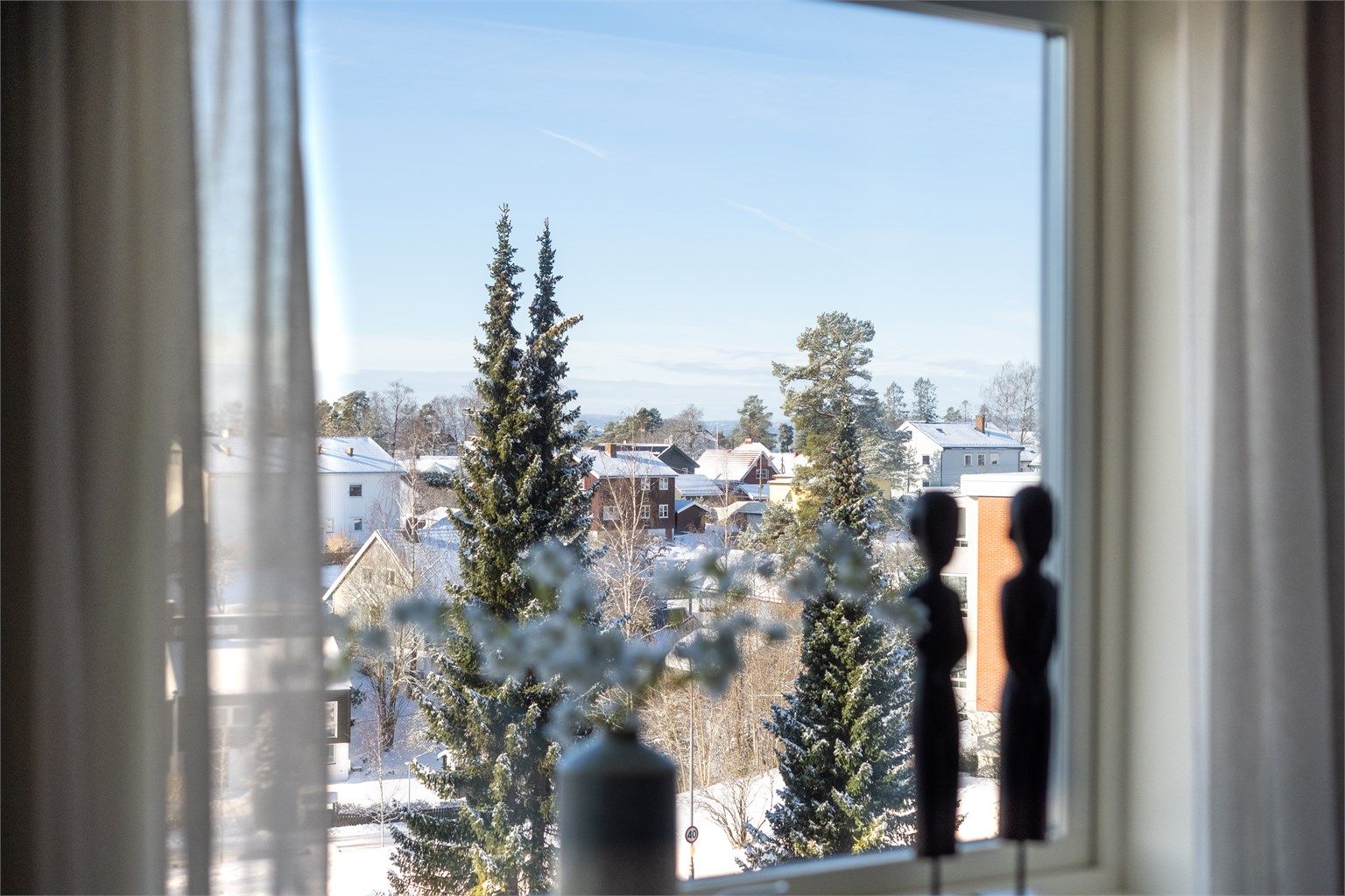 Fra vinduene har man en åpen og grønn utsikt over et rolig boligområde.