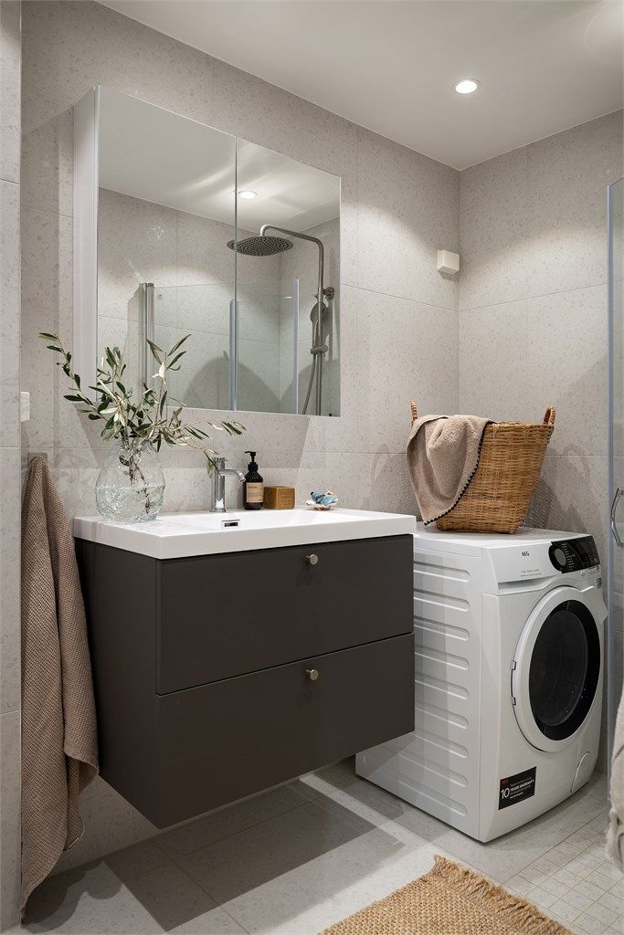 Badet er utstyrt med vegghengt toalett, dusjsone med glassvegger, servant med innredning og opplegg for vaskemaskin. 