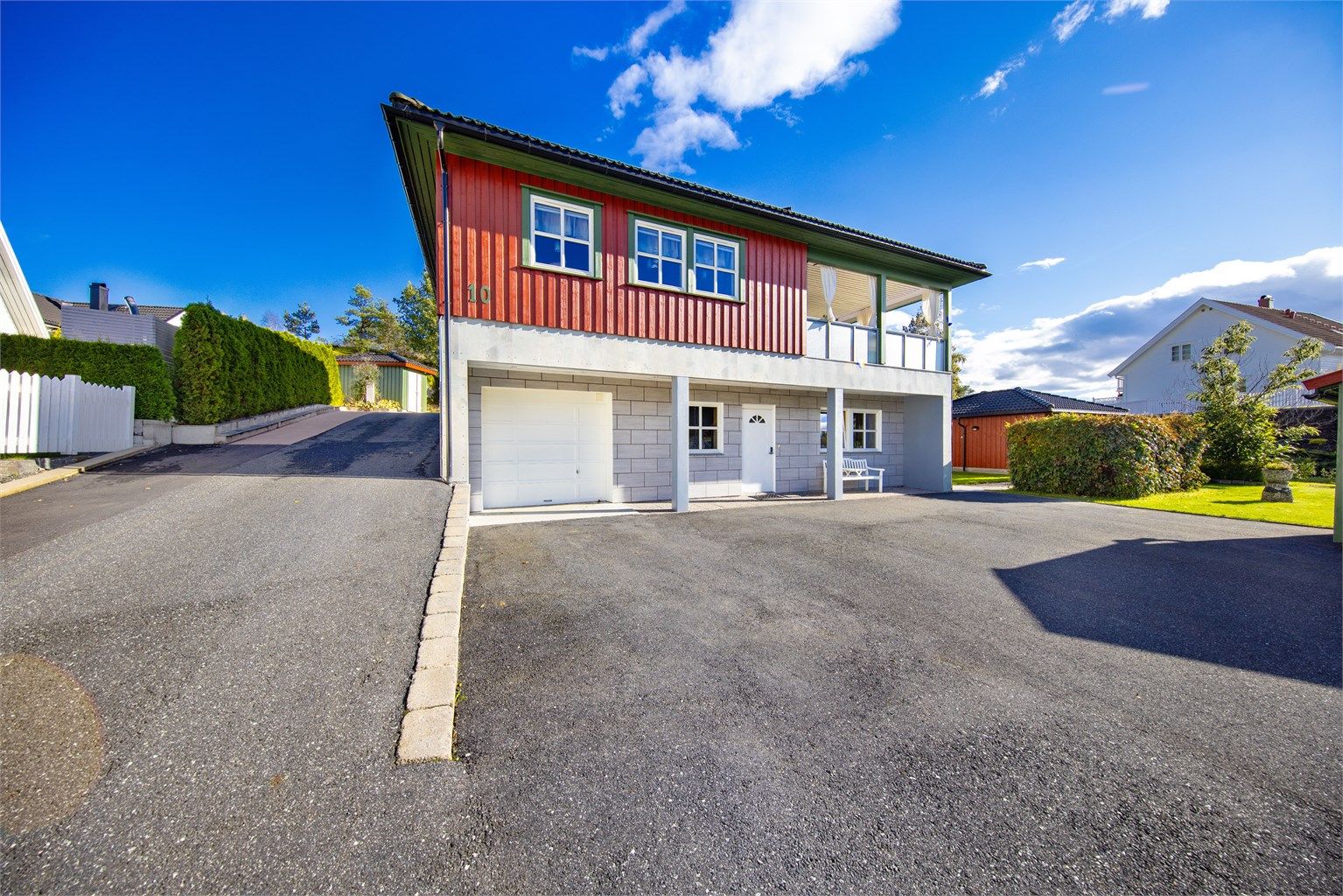 Flis er benyttet i stor utstrekning inne i boligen, men også grunnmuren er flislagt. Garasjen til høyre har port med elektrisk åpner og bod i bakkant.