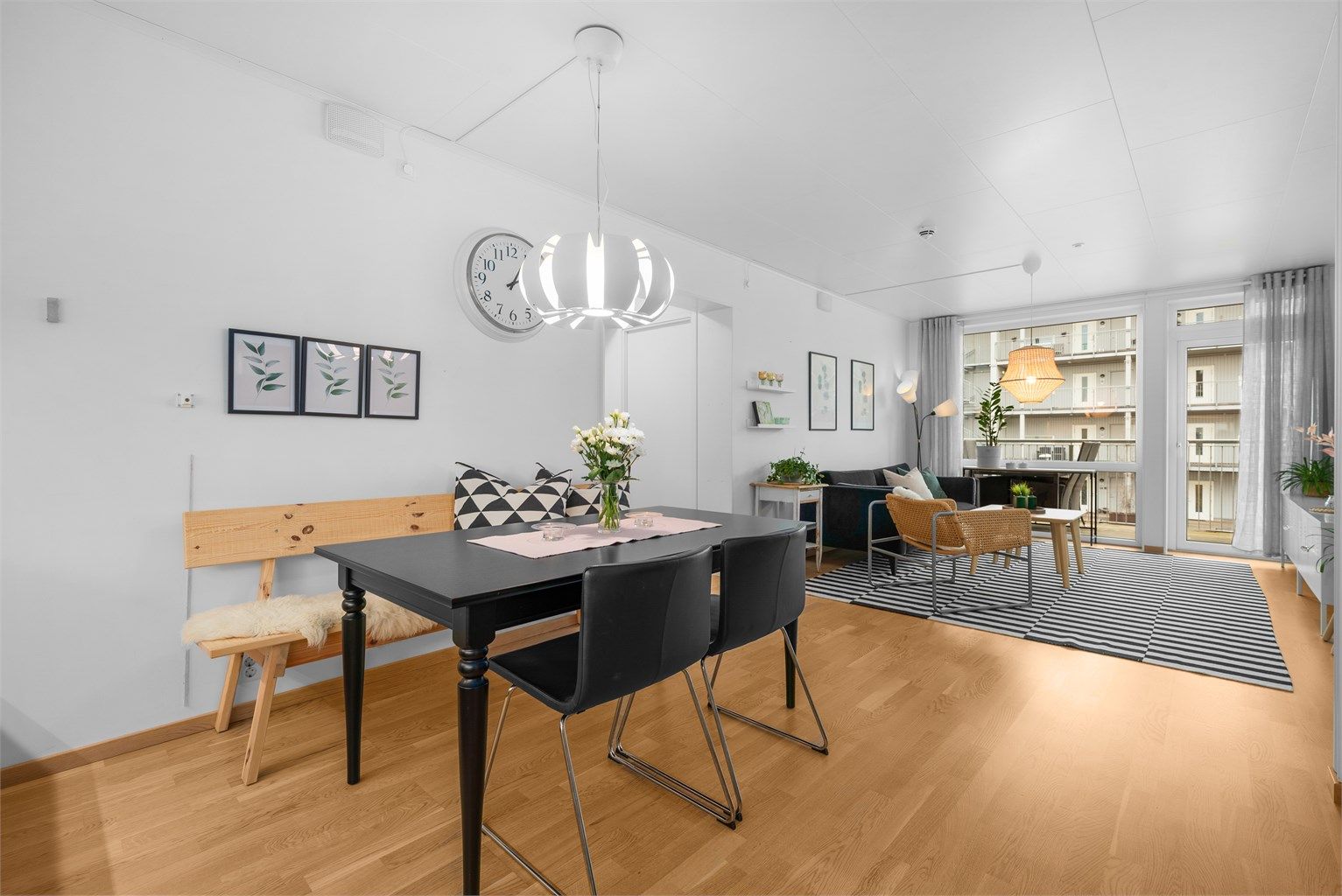 En åpen og sosial planløsning mellom stue og kjøkken, med gjennomgående tre-stavs parkett som skaper en helhetlig følelse.