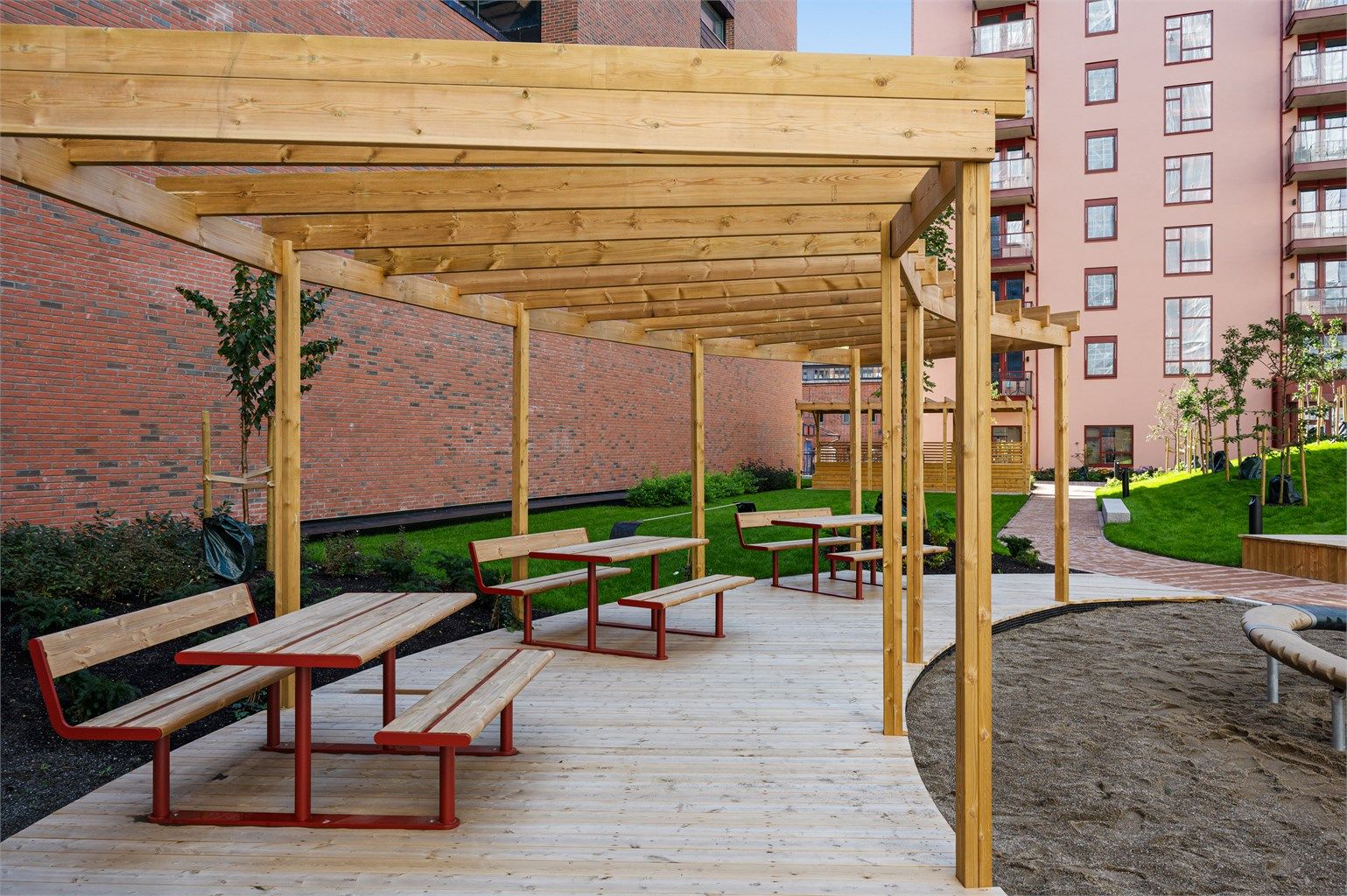 Felles gårdsrom med trepergola og sittebenker for beboerne.