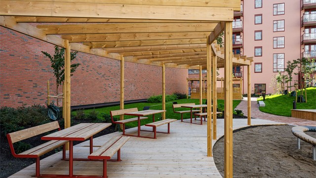 Felles gårdsrom med trepergola og sittebenker for beboerne.
