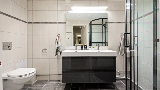 Badet har varmekabler og fliser på gulv og vegger. Dobbel servant gjør det mulig for to personer å benytte badet samtidig.