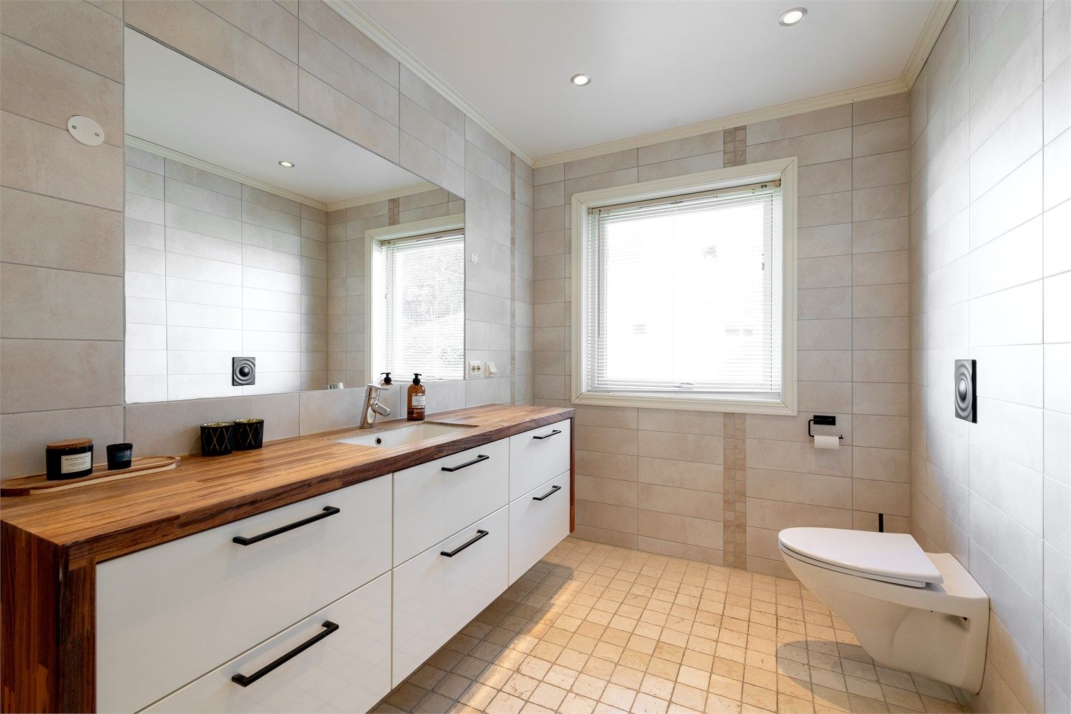 Stor og innholdsrik baderomsinnredning med god oppbevaringsplass. Vegghengt toalett. Innfelt speil i vegg