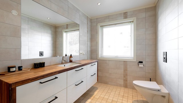 Stor og innholdsrik baderomsinnredning med god oppbevaringsplass. Vegghengt toalett. Innfelt speil i vegg