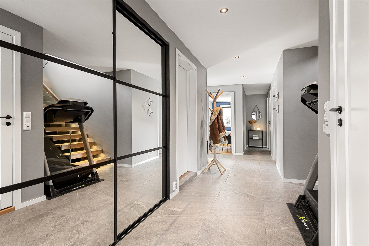 Hall/trapperom med en stor skyvedørsgarderobe med speilfronter som gir rikelig med oppbevaringsplass for yttertøy og sko