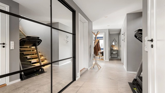 Hall/trapperom med en stor skyvedørsgarderobe med speilfronter som gir rikelig med oppbevaringsplass for yttertøy og sko